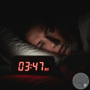 An alarm clock illuminating a tired face in the dark, with numbers showing the late hours of the morning.